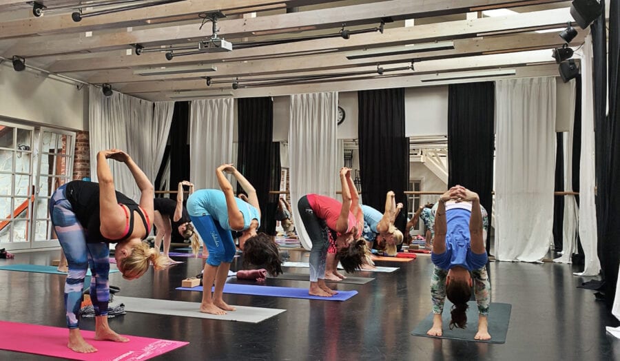 Jogíni ve skupinové praxi na jógovm víkendu předklonových pozic procvičující flexibilitu ramen